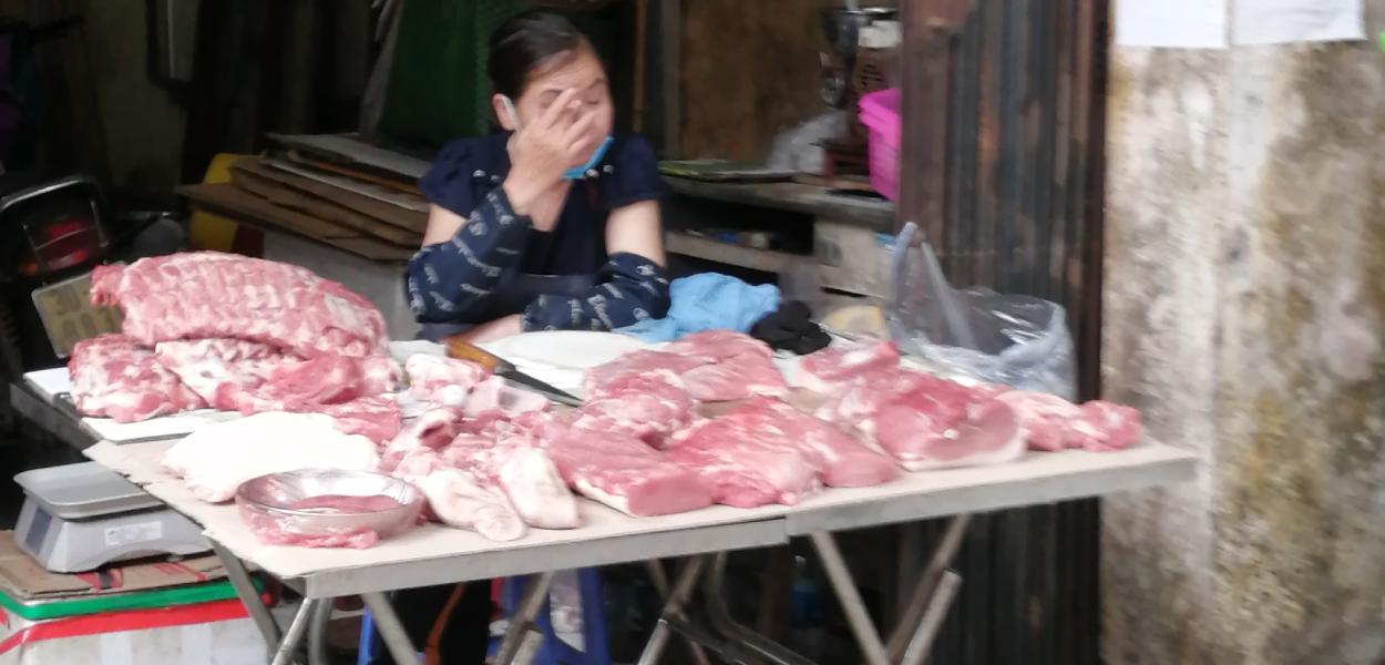 A lady selling pork on a stall