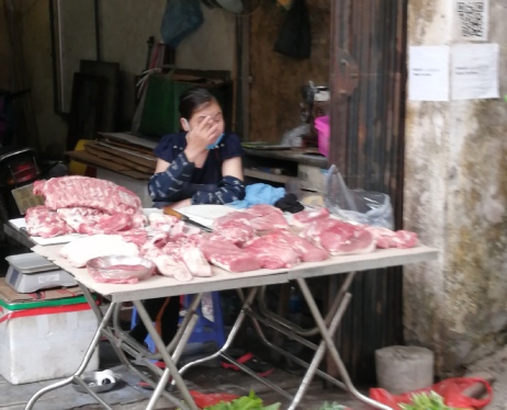 A lady selling pork on a stall